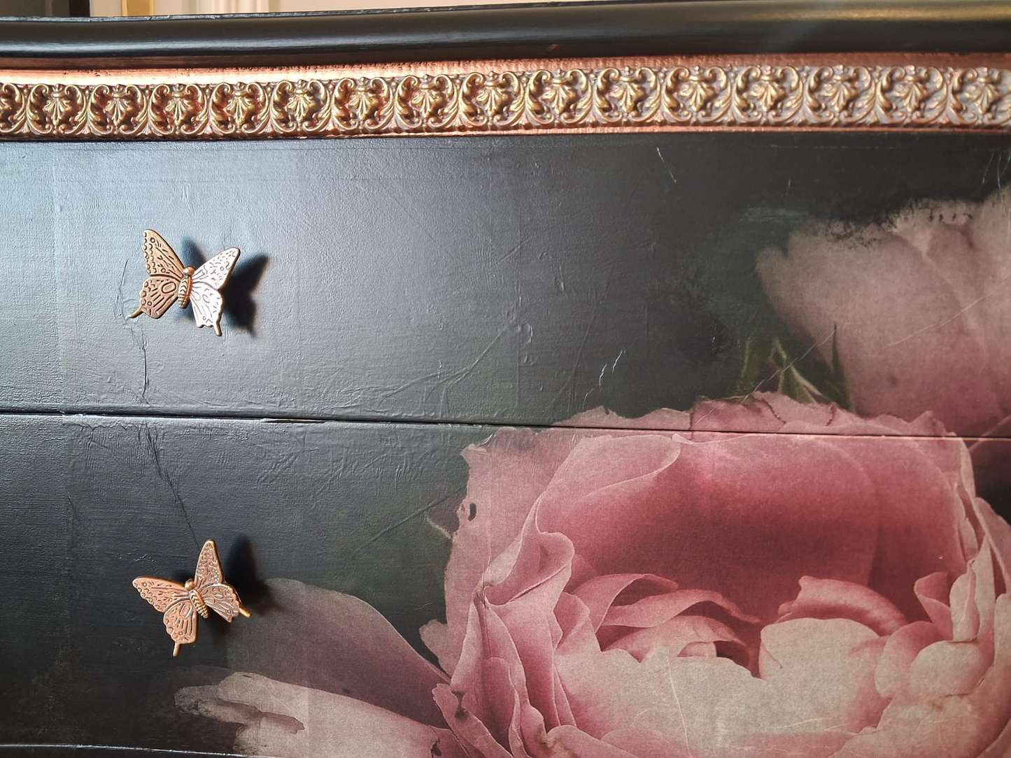 iradores mariposa de bronce en cómoda vintage con acabado artesanal
