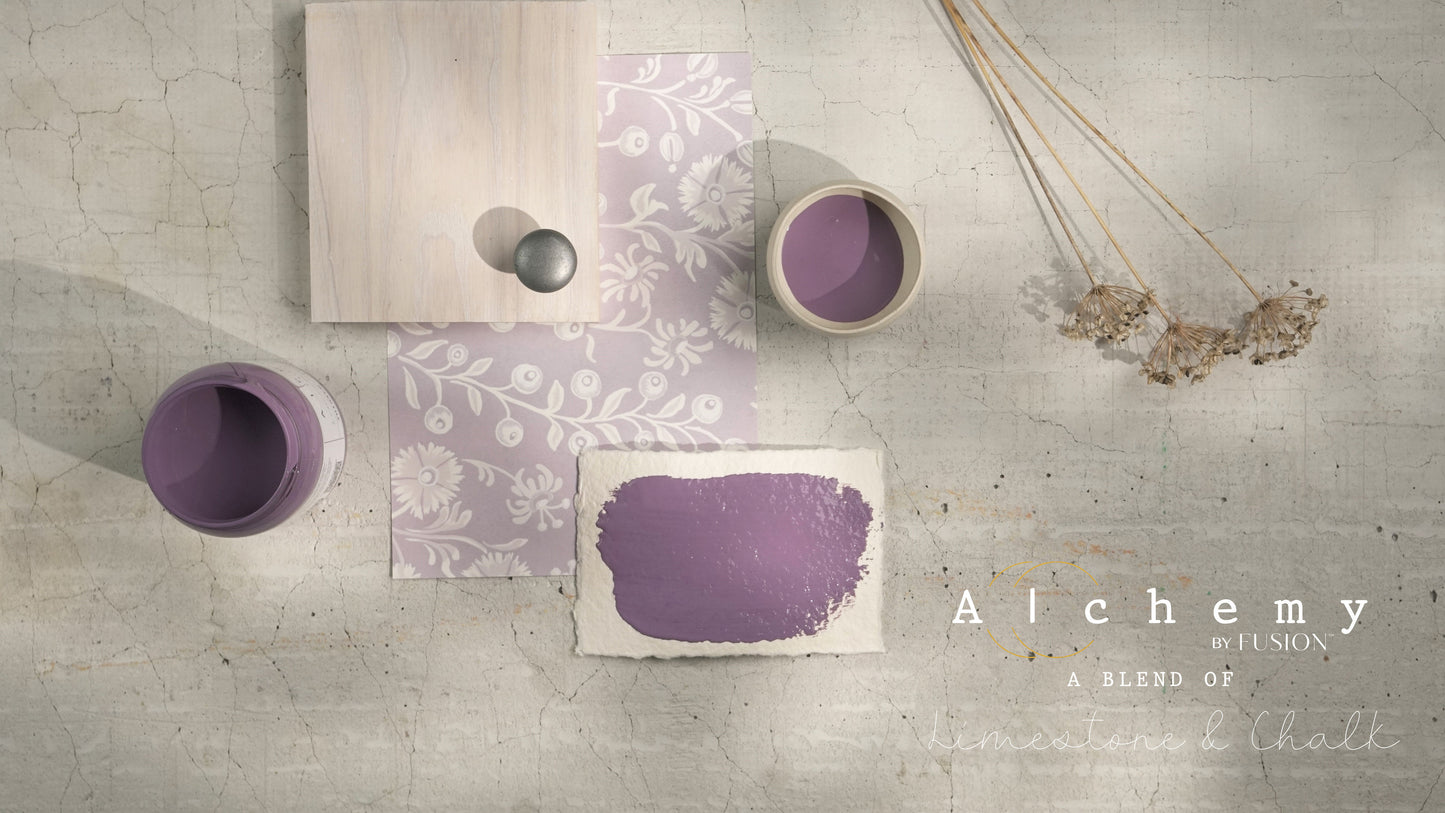 Flatlay inspiracional Alchemy by Fusion Thistle con muestra de color malva, botes abiertos, papel estampado floral, tirador cerámico gris y flores silvestres secas sobre fondo de azulejo craquelado