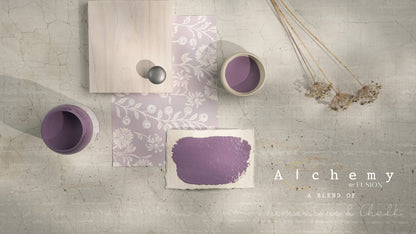 Flatlay inspiracional Alchemy by Fusion Thistle con muestra de color malva, botes abiertos, papel estampado floral, tirador cerámico gris y flores silvestres secas sobre fondo de azulejo craquelado