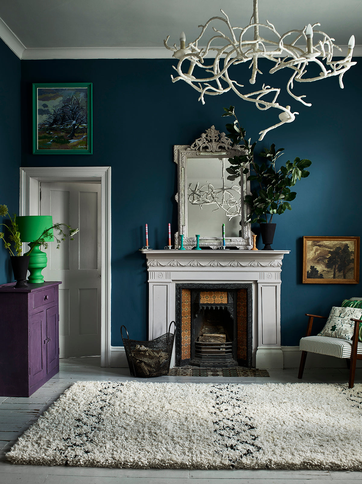 Salón con pared en Aubusson Blue, chimenea y espejo Paloma, lámpara Giverny, cómoda Rodmell y cojín Dulcet, Annie Sloan