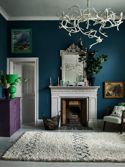 Salón con pared en Aubusson Blue, chimenea y espejo Paloma, lámpara Giverny, cómoda Rodmell y cojín Dulcet, Annie Sloan