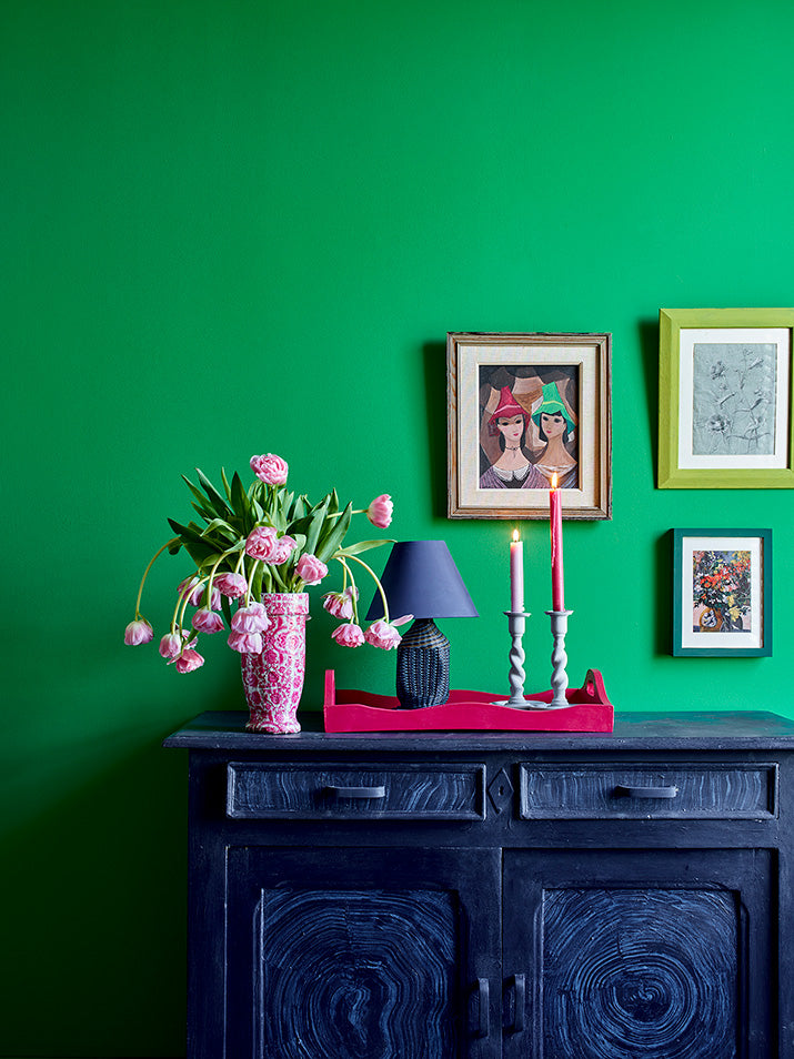 Salón con pared en Wall Paint Schinkel Green, aparador en Oxford Navy con detalles en Old White, bandeja en Capri Pink y marco Firle de Annie Sloan