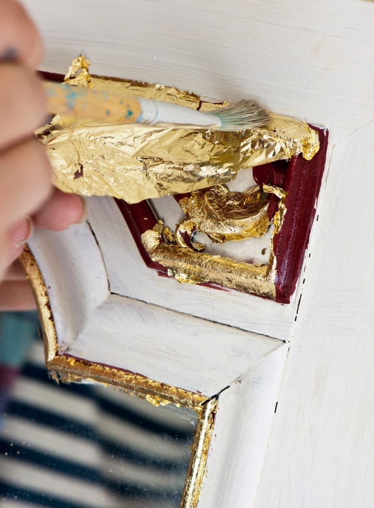 Aplicación de pan de metal suelto en oro sobre un espejo pintado con Chalk Paint™ en Burgundy y Old White