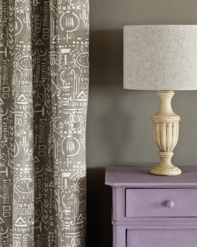 Composición decorativa con una mesita auxiliar pintada con Chalk Paint™ Emile de Annie Sloan, pared en French Linen, cortina Tacit en French Linen y pantalla en Linen Union de Old White