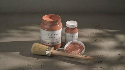 Botes Alchemy by Fusion Terracotta 500ml y 120ml con brocha sobre superficie de cemento, pintura a la tiza terracota cálido y terroso