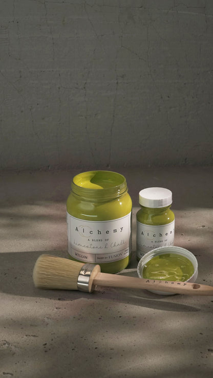 Botes Alchemy by Fusion Willow 500ml y 120ml abiertos con brocha redonda sobre fondo de cemento texturizado con luz lateral dramática, pintura a la tiza mostaza chartreuse limestone y chalk