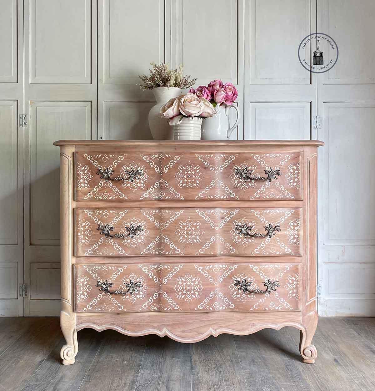 Stencil Modern Moroccan Kacha en cómoda rosa palo estilo Luis XV restaurada - patrón geométrico marroquí blanco en cajones, tiradores barrocos plateados - Re-Design with Prima - ambassador The Grandson's Brush
