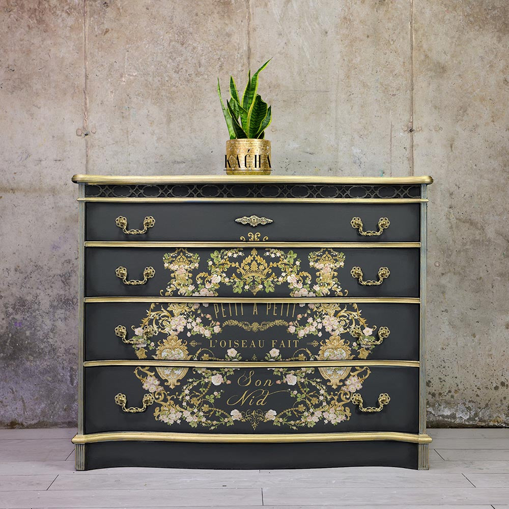 Transferencia decorativa Petit à Petit Kacha en cómoda negra con detalles dorados restaurada - arabescos florales dorados y texto Petit à Petit L'Oiseau Fait Son Nid en cajones - Re-Design with Prima

