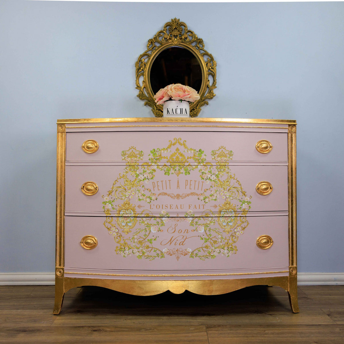 Transferencia decorativa Petit à Petit Kacha en cómoda rosa palo estilo Luis XVI restaurada con detalles dorados - arabescos florales dorados y texto Son Nid, espejo barroco dorado - Re-Design with Prima
