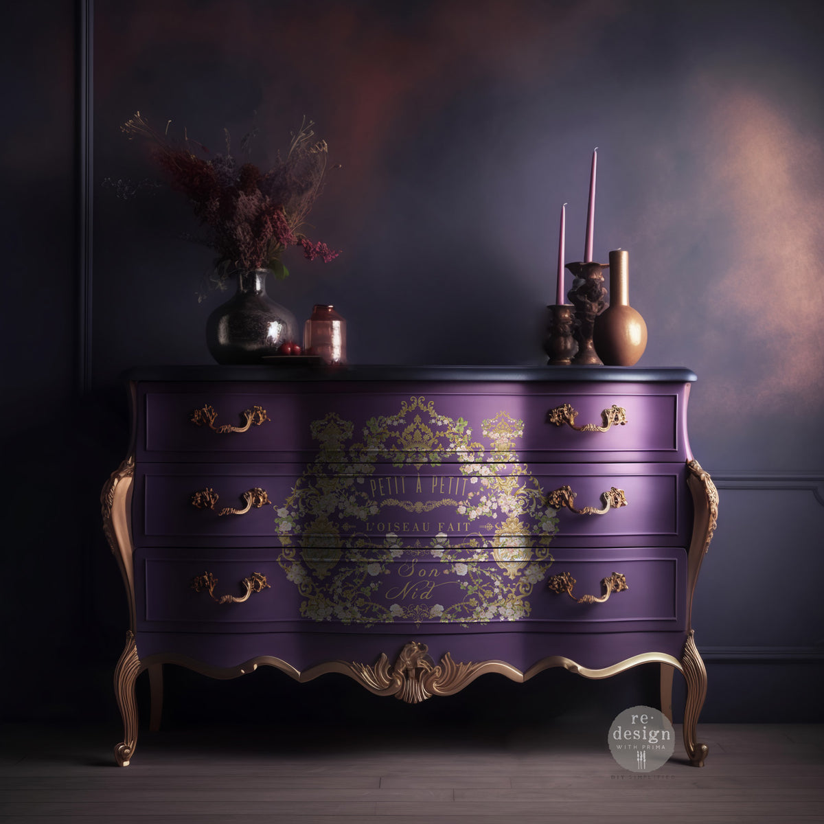 Transferencia decorativa Petit à Petit Kacha en cómoda bombé morada oscura estilo Luis XV restaurada - arabescos florales dorados y texto Petit à Petit L'Oiseau Fait Son Nid, ambiente dramático - Re-Design with Prima

